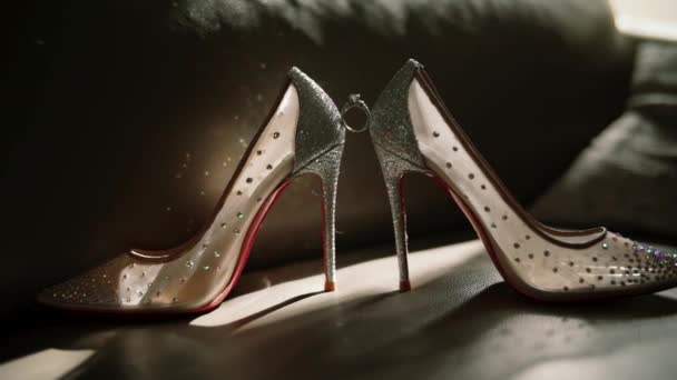Trauringe und Ohrringe an Schuhen mit Sonnenstrahlen. Accessoires für die Braut auf Schuhen. — Stockvideo