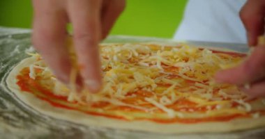 Orijinal İtalyan çiğ pizzası yapma süreci, geleneksel tarzda hazırlanma. Restorandaki hazırlıktan sonra pizzaya peynir ekleyen şef fırıncının eli. Yavaş çekim