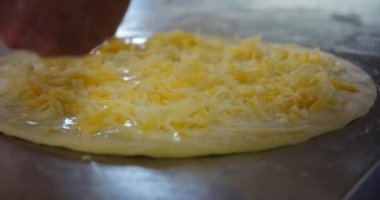 Orijinal İtalyan çiğ pizzası yapma süreci, geleneksel tarzda hazırlanma. Restorandaki hazırlıktan sonra pizzaya peynir ekleyen şef fırıncının eli. Ağır çekim. Ver 2
