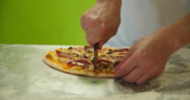 Şef pizza kesicisiyle pepperonili pizzayı dilimliyor. Yavaş çekim Ver 3
