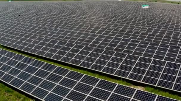 Vista aérea del dron. Granja de plantas de energía solar en verano con campos en el fondo Producción de energía limpia. Tiro medio. — Vídeos de Stock