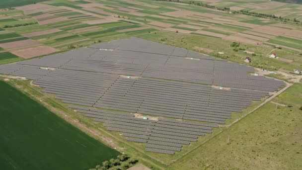 Вид с воздушного беспилотника. Солнечная электростанция ферма летом с полями на заднем плане Производство чистой энергии пролетел над — стоковое видео