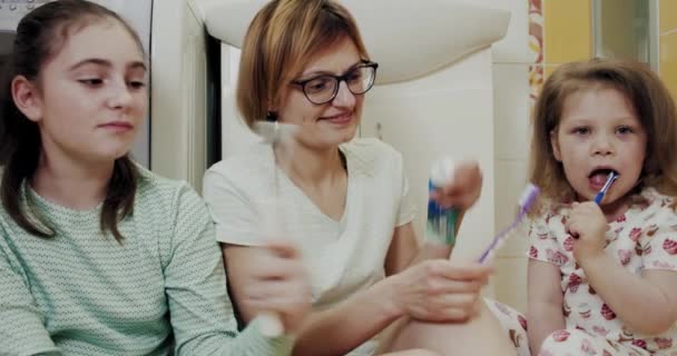 Mãe e duas filhas escovando os dentes juntos no banheiro — Vídeo de Stock