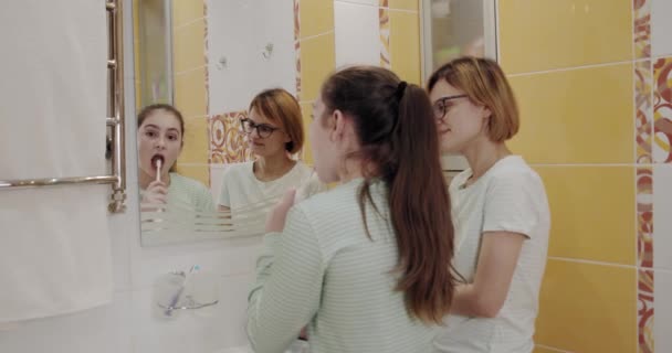 Mamá e hija cepillándose los dientes juntas en el baño . — Vídeos de Stock