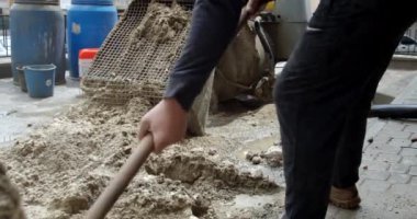 İşçi çimento makinesine kürekle kum atıyor.