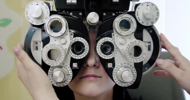 Eyesight measurement to young woman with optical phoropter. Woman doing eye test Slow motion Close up — Stock Video