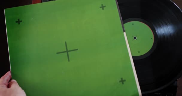 크롬 키를 가진 올드 비닐 플레이어, 맨 은 비닐 디스크를 꺼내서 녹색 화면의 플레이어 위에 놓습니다. 추적 지점. — 비디오