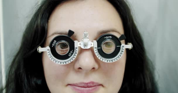 Chiudi la misurazione della vista a una giovane donna con phoropter ottico. Donna che fa il test degli occhi rallentatore — Video Stock
