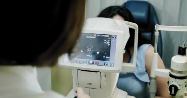 Oftalmología: comprueba los ojos de la doctora que trabaja con los ojos de la máquina de refractómetro probados. De cerca. . — Vídeos de Stock