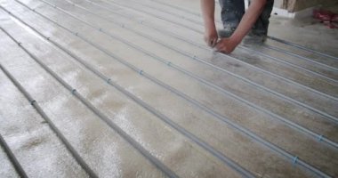 İşçi boruları ısı yalıtımlı bir zemin için izolasyona bağlıyor, döşeme su ısıtma için yeraltı ısıtma borularını çalıştırıyor. Isıtma sistemleri.