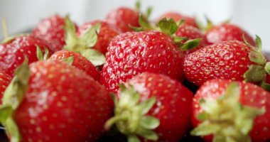 Taze çilekler, beyaz arka planda yavaşça dönüyorlar. Orta vuruş.