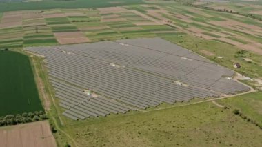 Hava aracı görüntüsü. Yazın arka planda tarlaları olan güneş enerjisi santrali V2 üzerinde uçan temiz enerji üretimi