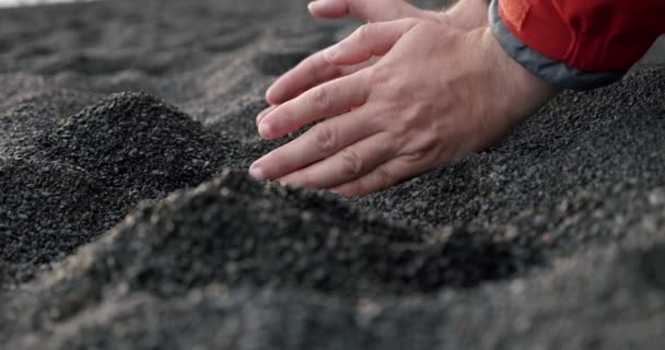 Zeitlupe der Männerhände nimmt den schwarzen Vulkansand, der sich am Reynisfjara Black Sand Beach durch die Finger ergießt. — Stockvideo