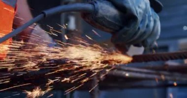 Ağır çekim yakın çekim. Metali öğütme makinesiyle kesen erkeklerin yan görüntüsü.