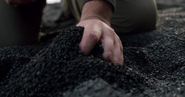 Zeitlupe der Männerhände nimmt den schwarzen Vulkansand, der sich am Reynisfjara Black Sand Beach durch die Finger ergießt. V3 — Stockvideo