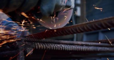 Ağır çekim yakın çekim. Metali öğütme makinesiyle kesen erkeklerin yan görüntüsü. V2