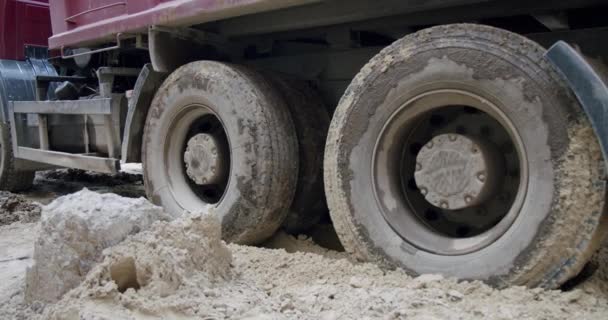 De wielen van een vrachtwagen gaan door een moeras op een bouwplaats. Sluiten. — Stockvideo