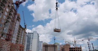 Crane, inşaat alanında, mimari dairelerde yük kaldırıp döndürüyor. Geniş açı