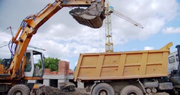 Graafmachine laadt zand in een vrachtwagen carrosserie op een bouwplaats, industrie. — Stockvideo