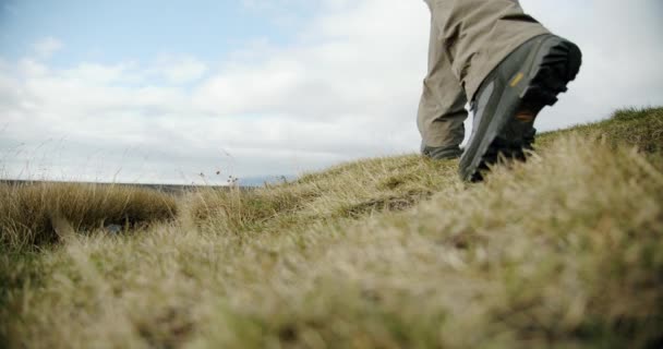 En närbild av en man ben i stövlar går på grön mossa och gräs i Island. — Stockvideo