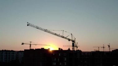 Sunset Light 'taki siluet vinçlerin hava aracı görüntüsü. Şehirdeki inşaat alanı binası. V2 üzerinde uçuyor