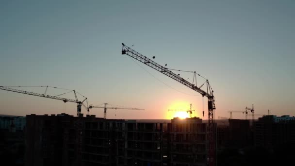 Vista aérea de Drone de las grúas de construcción de siluetas en Sunset Light. Edificio del sitio de construcción en City. V8 — Vídeo de stock