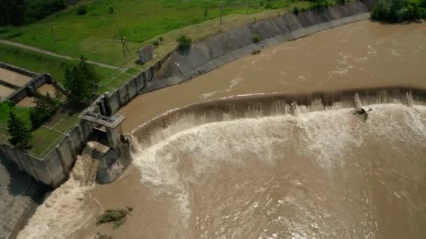 Drohnen aus der Luft. Flusswasser fließt nach schweren Überschwemmungen und Regenfällen von einem mit Wasser gefüllten Damm herab. Mittelschuss V5 — Stockvideo