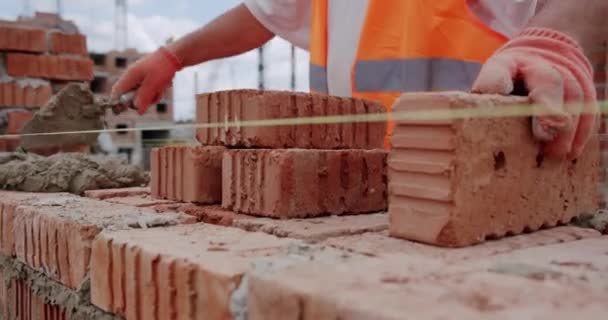 Hombre trabajador pone ladrillo en la pared con cemento usando paleta. Primer plano V2 — Vídeos de Stock