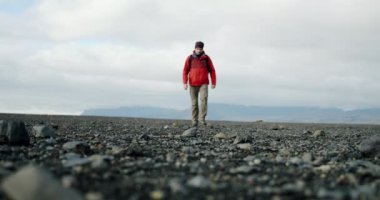 İzlanda 'da bir plajda siyah kumlar ve taşlar üzerinde yürüyen bir adamın bacakları..