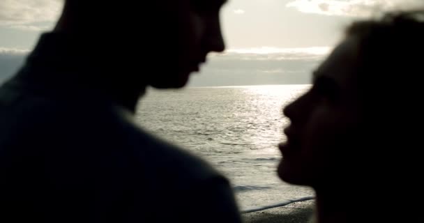 Silhouet Kussen bruidspaar staat tegen de zonsondergang op een strand in IJsland. Sluiten Slow motion — Stockvideo