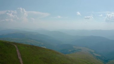 Hava aracı görüntüsü. Ağaçsız yeşil dağlar, mavi gökyüzünün arka planında Svydovets Dragobrat