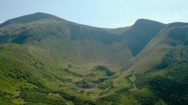 Hava aracı görüntüsü. Ağaçsız yeşil dağlar, dağlarda Dogyaska Gölü mavi gökyüzünün arka planında Svydovets Dragobrat