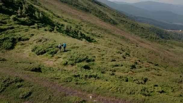 Veduta aerea drone di una coppia di viaggiatori uomo e donna con zaini che camminano insieme sulla montagna — Video Stock