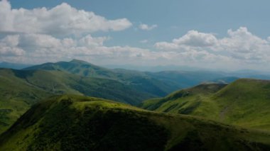 Hava aracı görüntüsü. Ağaçsız yeşil dağlar, dağlarda Dogyaska Gölü mavi gökyüzünün arka planında Svydovets Dragobrat V6