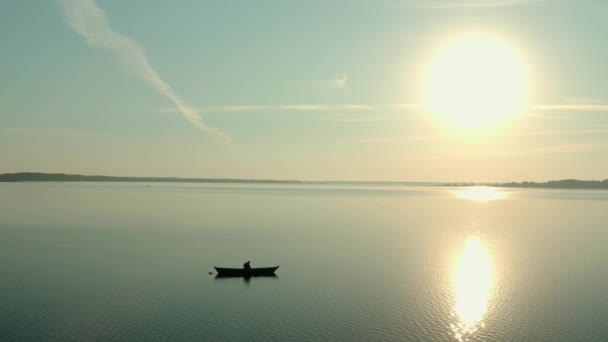 Воздушный беспилотник вид на рыбака на лодке на восходе солнца, утренняя рыбалка, плавание на спокойном озере на рассвете — стоковое видео