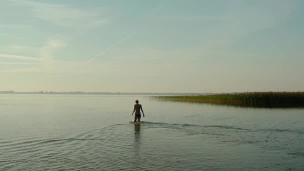 Вид на повітряний дрон, приваблива молода жінка, що йде в озері в літній день . — стокове відео