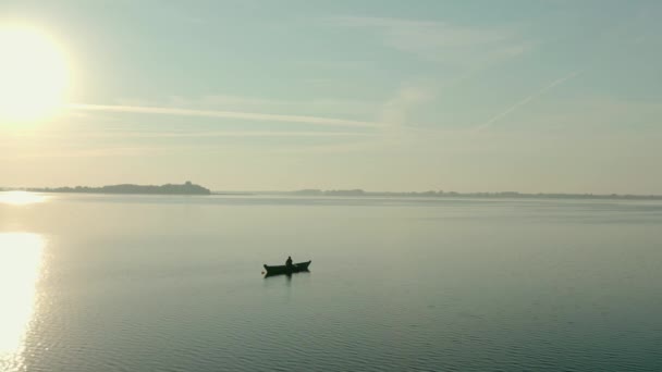 日の出のボートの上の漁師の空中ドローンビュー、朝の釣り、夜明けの穏やかな湖で泳ぐV2 — ストック動画