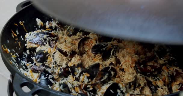 Slow motion, Open het deksel van de pan met kneden paella met garnalen, mossel, rijst, specerijen, saffraan in enorme paella pan. Sluiten. — Stockvideo