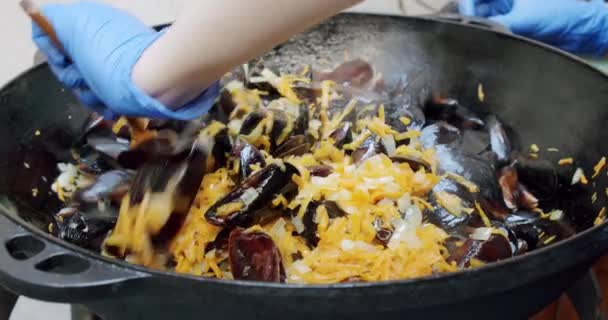 En cámara lenta, la cocina del chef amasa la paella con camarones, mejillones, arroz, especias, azafrán en una enorme paella. Primer plano V2 — Vídeos de Stock