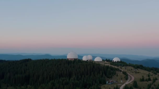 Vista aérea del dron, concepto de arquitectura inusual. salida del sol sobre la antigua estación de radar de diseño único Pamir en forma de esferas blancas en la montaña — Vídeo de stock