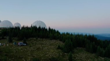 Hava aracı görüntüsü, alışılmadık mimari konsepti. Pamir 'in dağdaki beyaz küreler şeklinde dizayn edilmiş eski radar istasyonu üzerinde gün batımı.