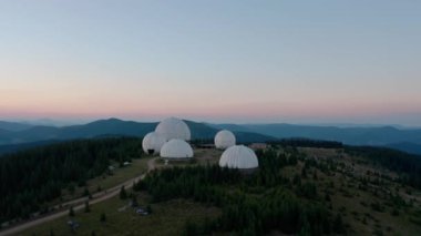 Hava aracı görüntüsü, alışılmadık mimari konsepti. Dağ V2 'de beyaz küreler şeklinde dizayn edilmiş Pamir eski radar istasyonu üzerinde gün batımı