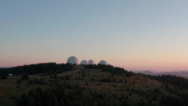 Vista aérea del dron, concepto de arquitectura inusual. salida del sol sobre una antigua estación de radar de diseño único en forma de esferas blancas en la montaña — Vídeo de stock