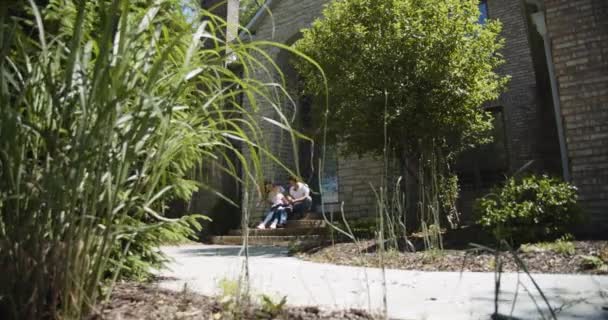 Familjen sitter tillsammans nära huset. Flytta kameran — Stockvideo