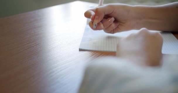 Großaufnahme weiblicher Hände schreibt Notizen aus weißem Papier — Stockvideo