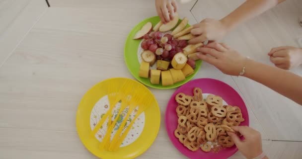Mny mains d'enfants prennent des fruits et des collations, vue de dessus — Video
