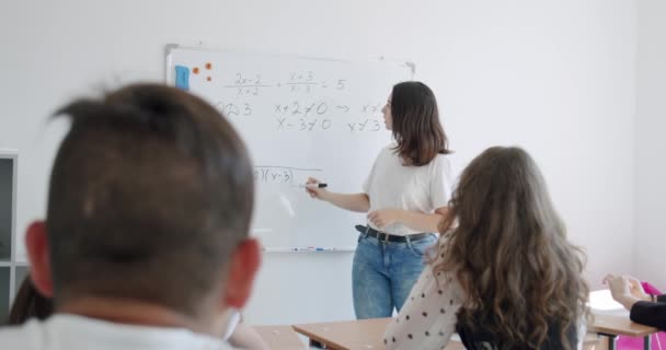 Lehrerin schreibt mathematische Formeln auf Whiteboard in einem Klassenzimmer. — Stockvideo