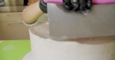 Yakın plan. Elinde metal spatulayla pastaya tereyağı kremi süren bir kadın. V2