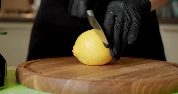 Кук тримає лимон в кулаках стиглі фрукти в дві половини з легким рухом ножа. Зачиніть. — стокове відео