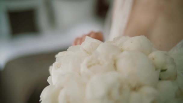 Le matin de la mariée dans une rose blanche tient dans ses mains un bouquet de roses de mariage. Gros plan. — Video